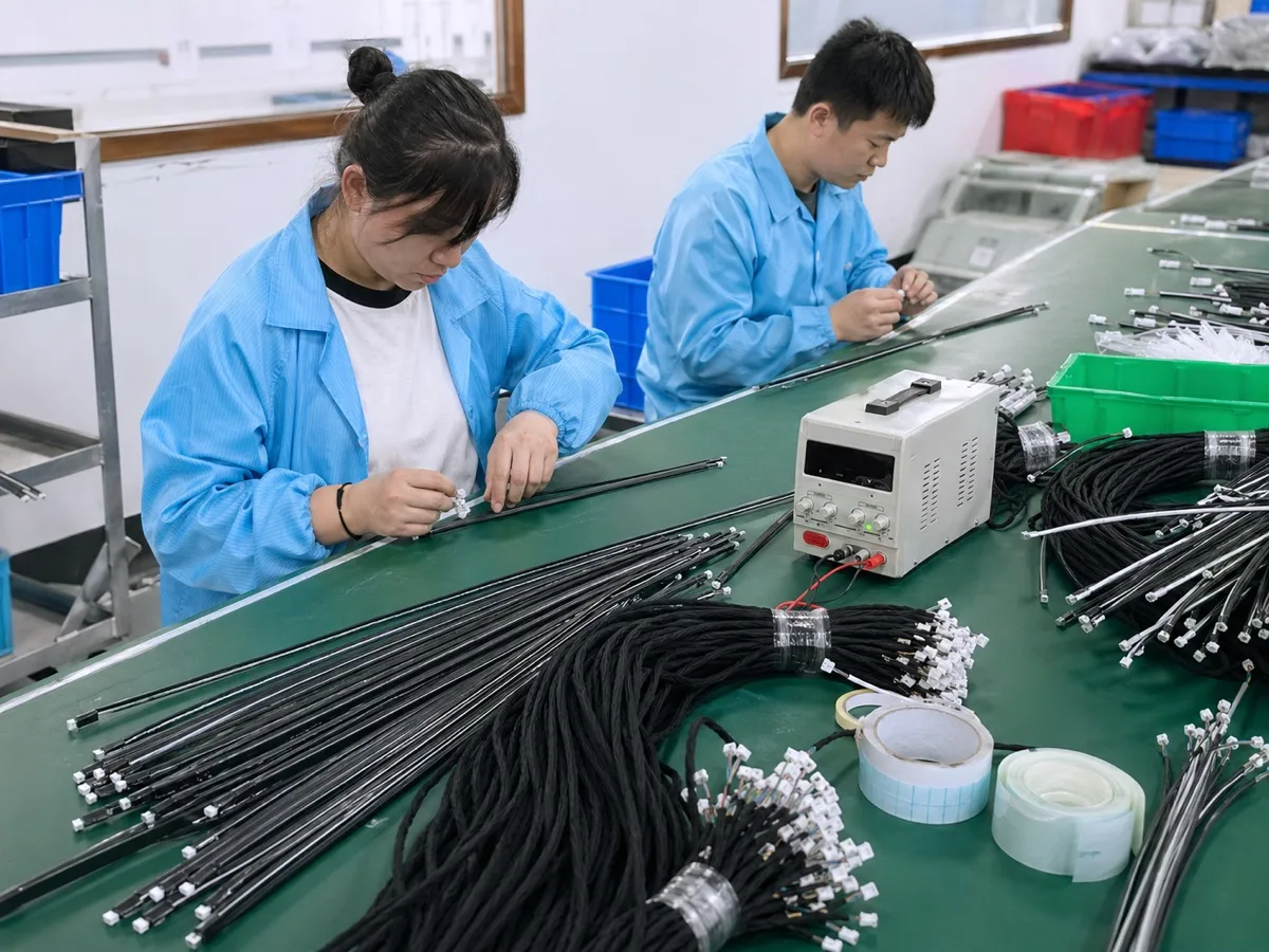 Real production workbench with operators checking lighting wiring assemblies