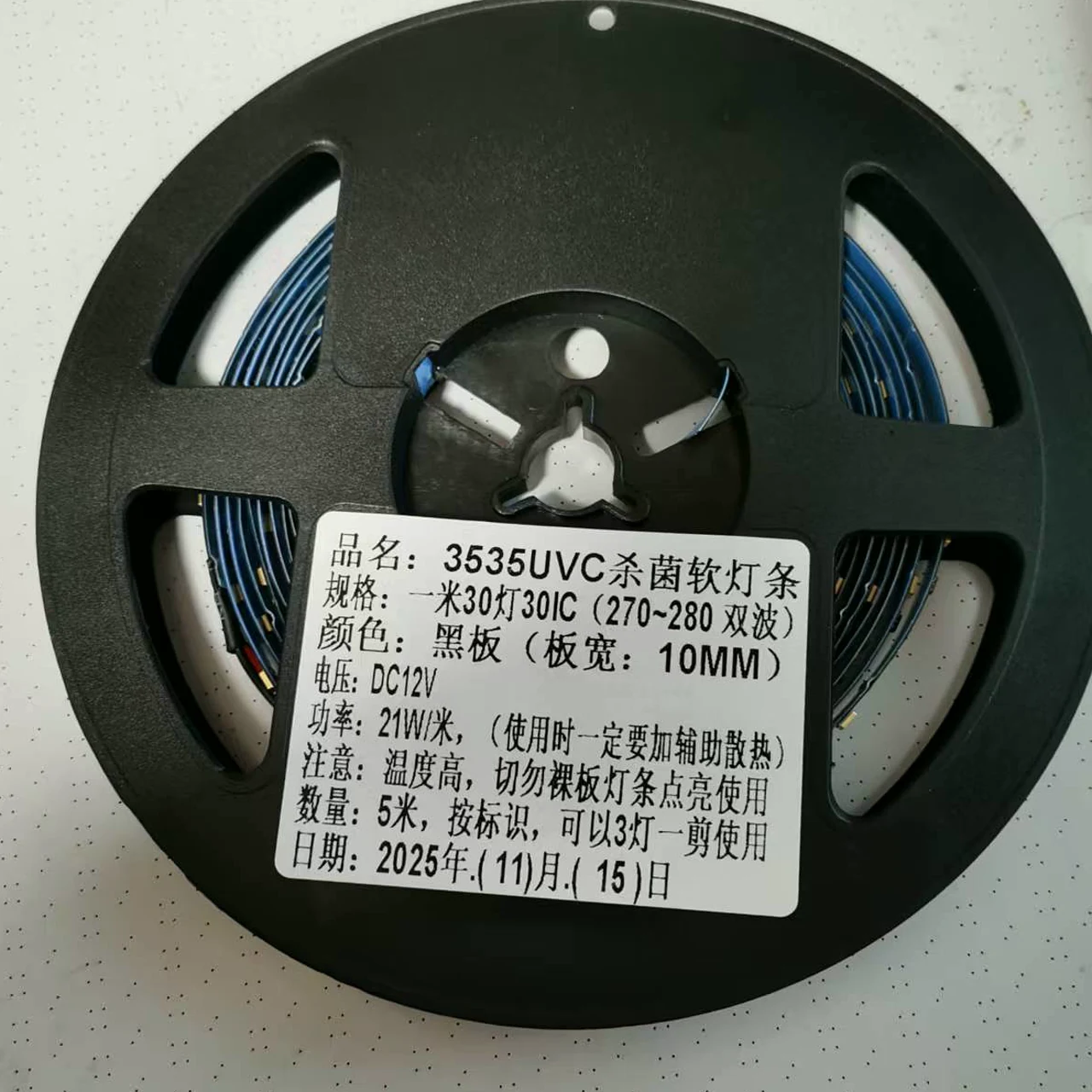 Reel of black UVC flexible LED strip with a Chinese production label showing batch-specific reference data